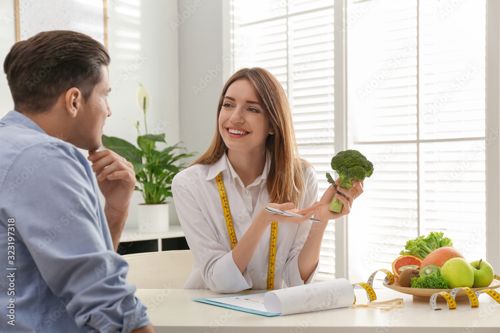 Canvas Prints Young nutritionist consulting patient at table in clinic