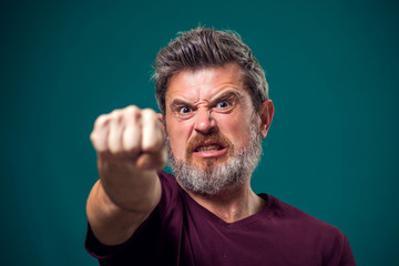 A portrait of bearded angry man showing fist at camera. People and emotions concept