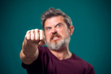 A portrait of bearded angry man showing fist at camera. People and emotions concept