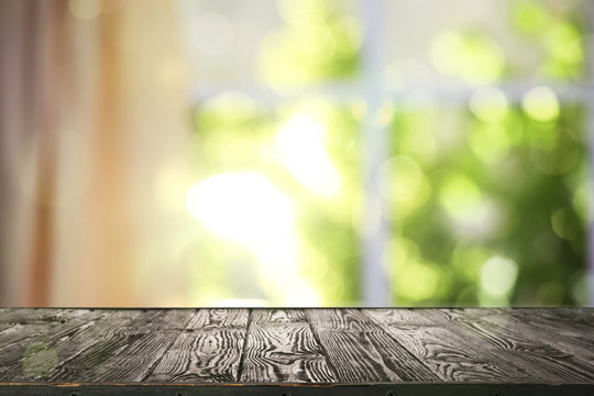 Wooden table and blurred view through window on garden in morning. Springtime