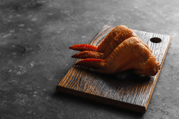 Smoked chicken wings on a wooden table and dark background side view