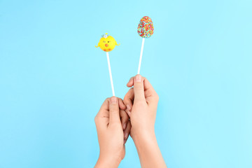 Woman with delicious cake pops on light blue background, closeup. Easter holiday