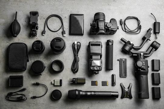 Flat lay composition with camera and video production equipment on light grey stone background