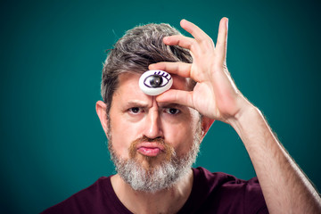 A portrait of bearded man holding egg with drawing eye behind forehad as third eye symbol.