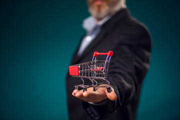 Man in suit holding small shopping trolley in hand. Business, commerce and shopping concept