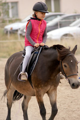 Obraz premium young girl learns to ride a horse