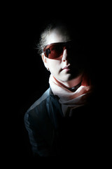 Girl in sunglasses in the rays of sunlight. On a black background.