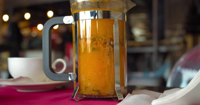 Bright yellow sea buckthorn tea is brewed in a french press teapot. Coffee shop. BMPCC4K