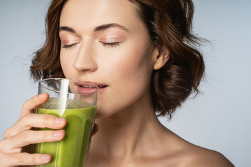Relaxed brunette female person drinking green smoothie