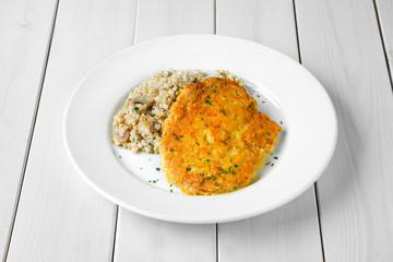 Schnitzel with green buckwheat on white wooden table