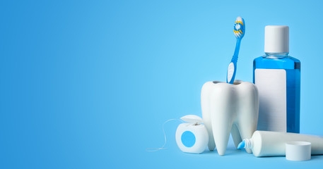 Set for cleaning teeth and mouth. Toothpaste, toothbrush, dental floss and mouthwash on a blue background. Copy space for text - obrazy, fototapety, plakaty