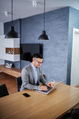 Classy handsome smiling caucasian unshaven businessman in suit sitting at dining table at home and...