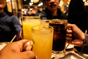 group of friends enjoying drink cocktails glasses, Team Asian People toasting, saying cheers holding tropical blended fruit margaritas. orange and sparkling water drinks. night life,alcohol,friendship