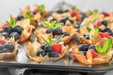 Freshly baked phyllo cups with blueberries, raspberries and whipped cream