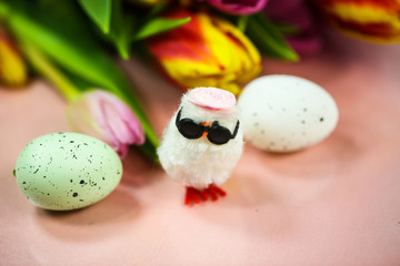lustiges Küken mit Ostereiern und Tulpen