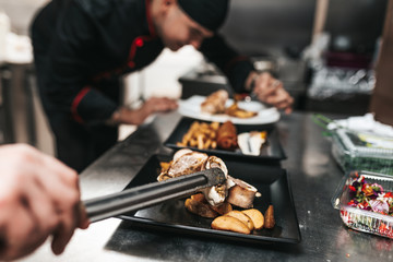 Professional chef arranging food plate with meat and vegetables.