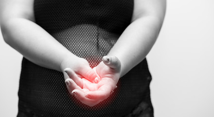 Overweight young woman massaging her arthritic hand and wrist or finger pain. concept of health care, medical, Obesity and arthritis. black and white image with red highlight point on hand