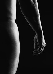 Detail of muscular man arm and buttocks against a black background