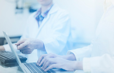 close up hands of scientist team on keyboard  while  using laptop Analyzing Statistics or Research in the laboratory. Health and Medical specialist doctor working in lab ,Studying