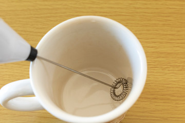 ミルク泡立て器と空のコップ