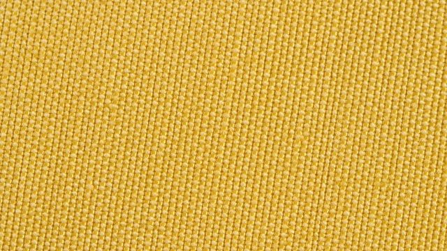 Textile background - yellow cotton polyester raincoat fabric. Weave pattern of threads close up. Macro shoot.
