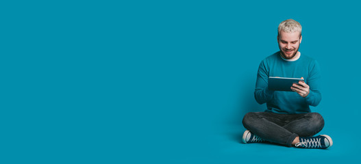 The photo of a student surfing on a tablet and sitting near the freespace looking attentive for something