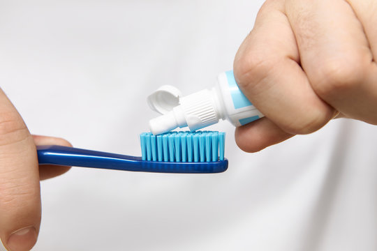 Close up image of man’s hands holding tube, squeezing whitening toothpaste on brush. Cropped shot of young male going to clean oral cavity after having meal. Hygiene, care and healthy lifestyle