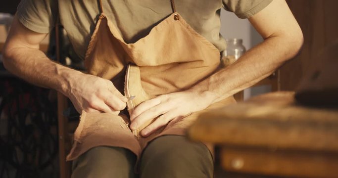 Traditional bespoke shoemaker cutting shaping leather insole on wooden shoe last with knife