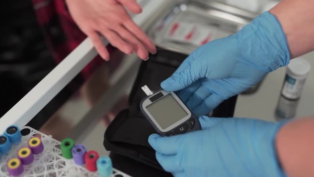 Close-up, the doctor prepares a glucose meter for a blood sugar test