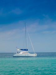 Sea view of a white yacht sailing in blue-green sea with cloudy and blue sky background, Phi Phi islands, Krabi, southern of Thailand.