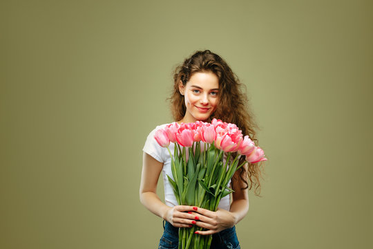 Young Girl Holding Bouquet Of Pink Tulips Flower Against Green Background