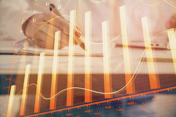 Double exposure of woman's hands making notes with forex graph hologram. Concept technical analysis.
