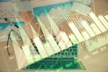 Double exposure of market chart with man working on computer on background. Concept of financial analysis.