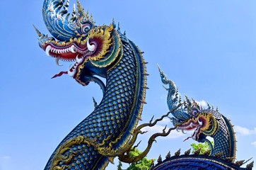 Fototapeta premium Beautiful blue naga sculpture (Thai dragon) on the blue sky background. Unique Blue Temple (Wat Rong Suea Ten)