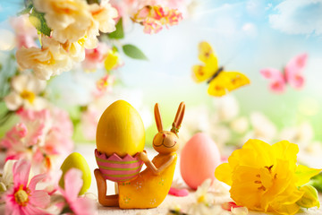 Easter decoration with bunny, Easter eggs and beautiful spring flowers on a blurred light background. Easter concept with copy space