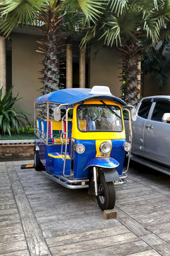 Blue and yellow Thai traditional taxi Tuk Tuk on the street parking, Thailand
