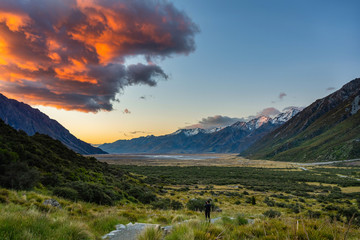 Tourists taking pictures on high mountains enjoying beautiful scenery, Morning skies and beautiful dramatic clouds in Mount Cook National Park, Aoraki, New Zealand.