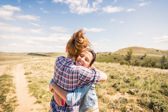 Two best girlfriends hanging out in the foothills having fun, hugging. Bridger, Montana, USA