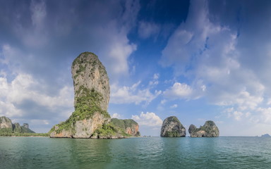 Fototapeta na wymiar view of high cliff rock mountain in the sea with cloudy and blue sky background, Railay Bay, Krabi, southern of Thailand.