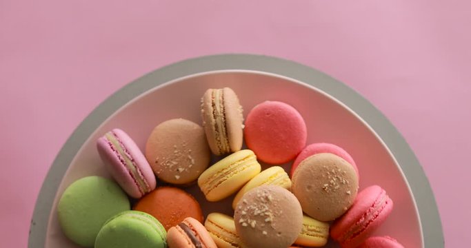 Female hand take one green macaroon from rotating colorful cakes set, copyspace
