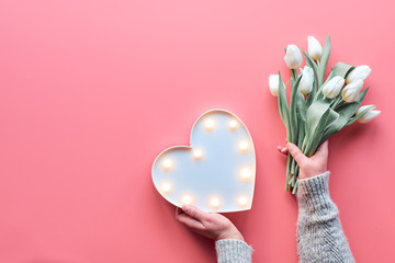 Springtime flat lay on pink, female woman hands holding bunch of white tulips, Spring flowers....