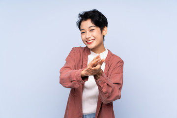 Young Asian girl over isolated blue background applauding after presentation in a conference
