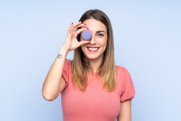 Fototapeta premium Young blonde woman over isolated blue background holding colorful French macarons