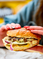 Woman hand holding a fresh burger before eating on street cafe