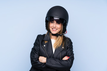 Young blonde woman with a motorcycle helmet over isolated blue background