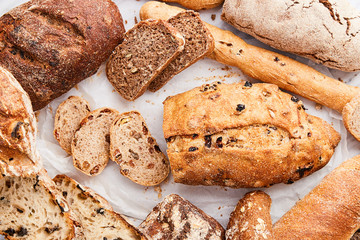 Breads variety on a marble background viewed from above. Various whole grain breads selection. Top view