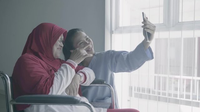 Old Muslim woman takes selfie photo with her nurse