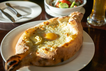 Khachapuri in Georgian restaurant - Georgian national cheese bread product, pie stuffed with cheese and eggs - Adjara Khachapuri is a famous dish from Georgia