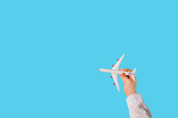 Toy model airplane in the hand of a child and on a sky blue background. Copy space.