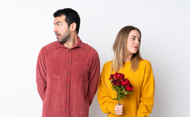 Couple in Valentine Day holding flowers over isolated background nervous and scared